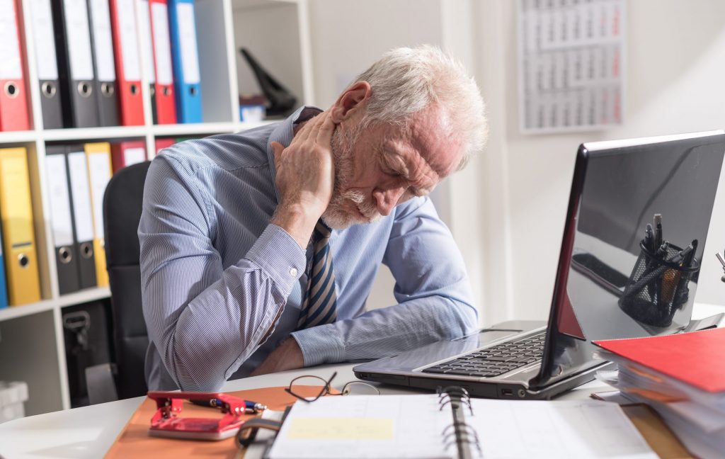 Man at desk at work with pain in neck looking for Neck Pain Treatment Clearwater.